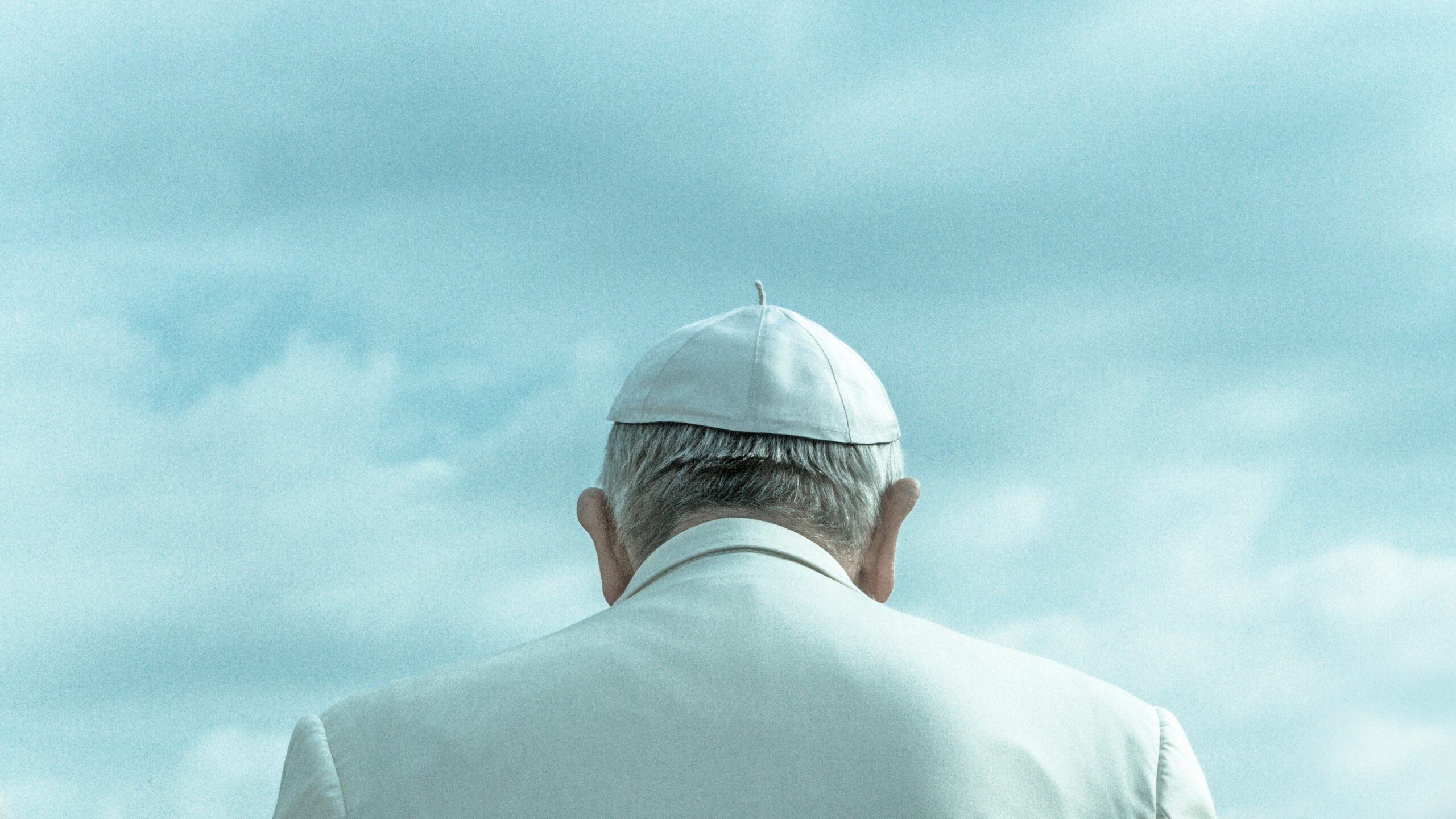 Person wearing white cap looking down under cloudy sky during daytime